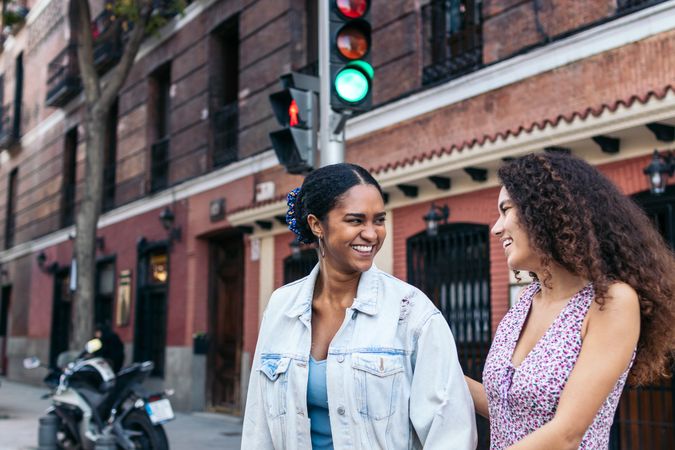 Two women talking while waiting at the pedestrian crossing