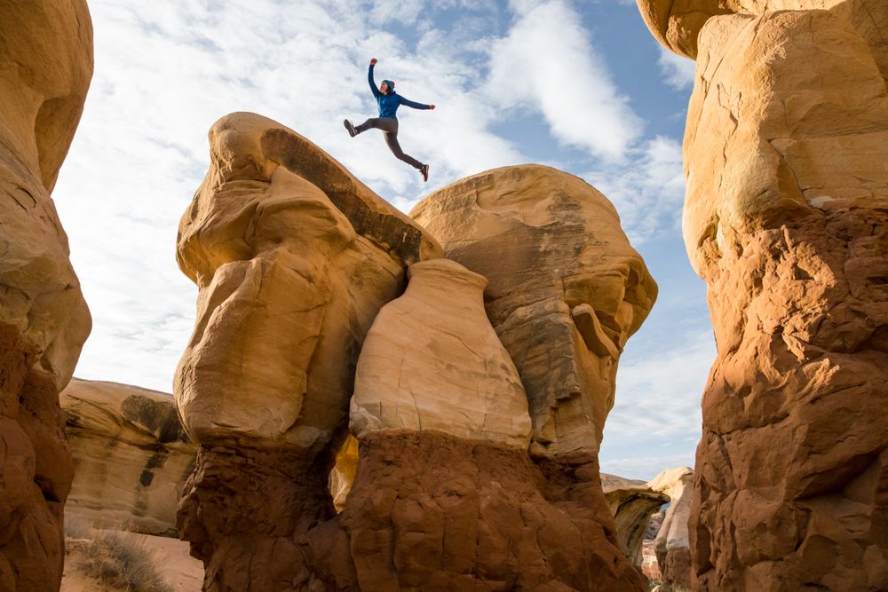 Person jumping beside rocky formation