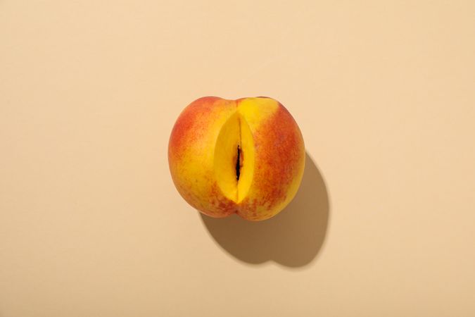 A peach with a cut on a light background.