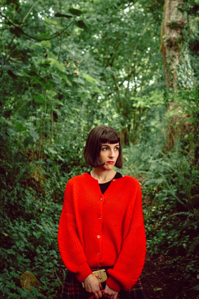 Woman in red with big red suitcase in forest