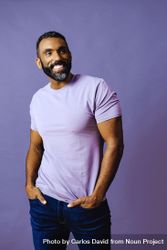 Smiling male in purple studio with hands in pocket, vertical 479jO0