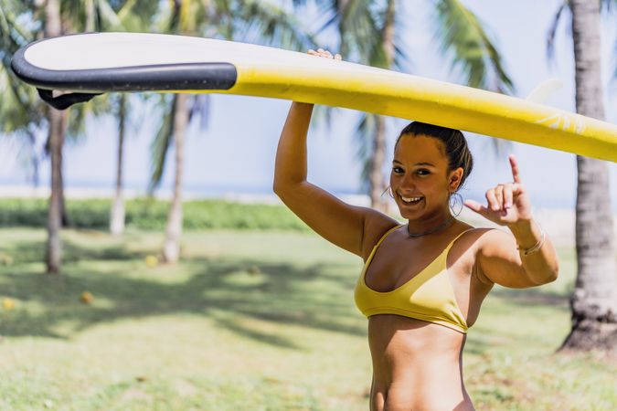 Woman in bikini with bright paddleboard on beach
