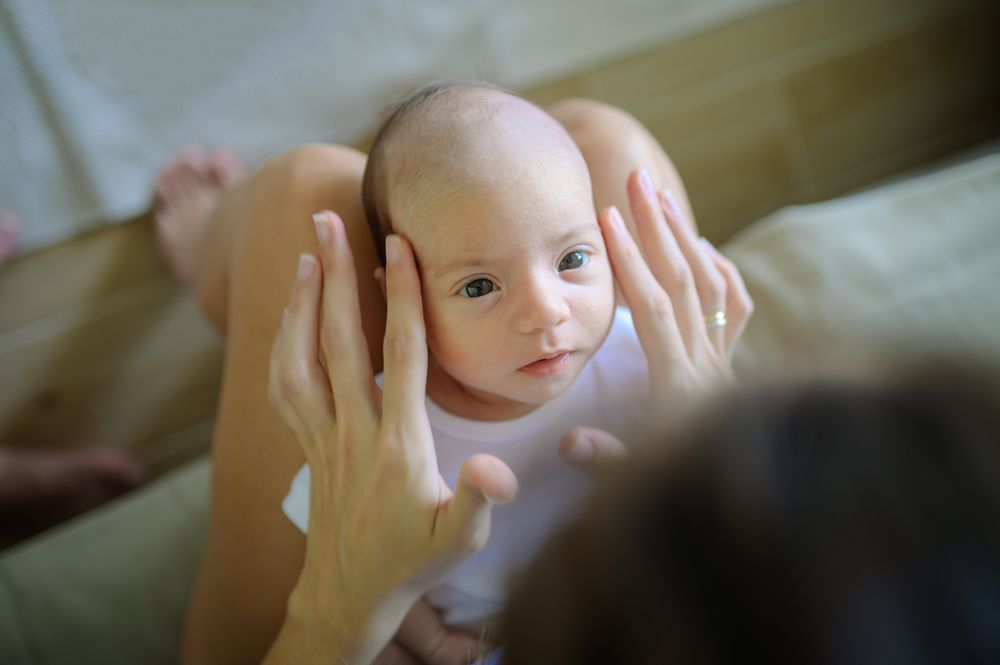 Mother caressing infant on sofa