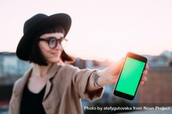 Woman at dusk with glasses and hat with smart phone outside 4jaBv5