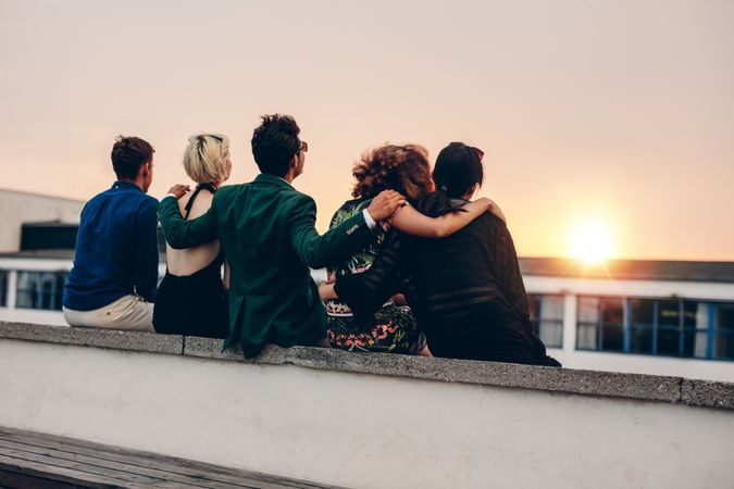 Group of friends with arms linked watching the sunset
