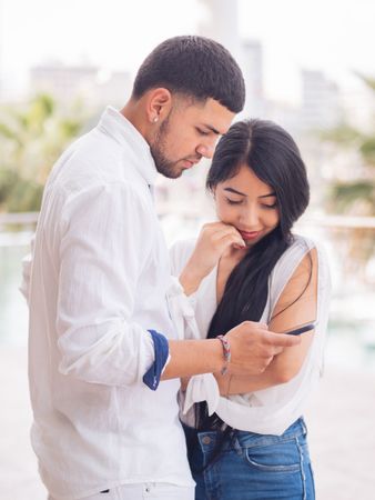 Man messaging on smartphone standing with woman