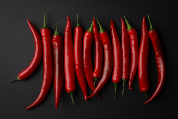 Chilli peppers on dark background, top view