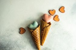 Two ceramic hearts in waffle cones on grey background with various Valentine ornaments