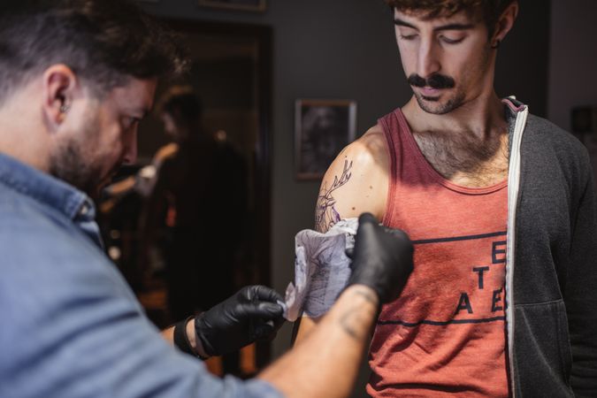 Tattoo master removing template on client's forearm