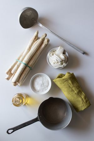 Asparagus and cream amidst kitchenware and condiments