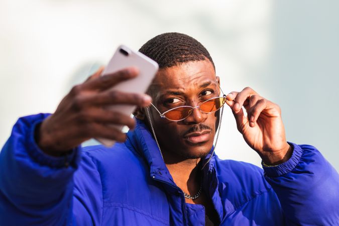 Trendy Black man taking selfie in city