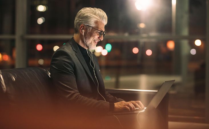 Man in business attire and eye glasses working late at office with laptop