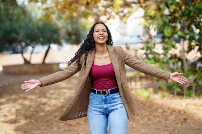 A Joyful Woman Embracing the Beauty of Nature in an Autumn Park During Daytime Hours