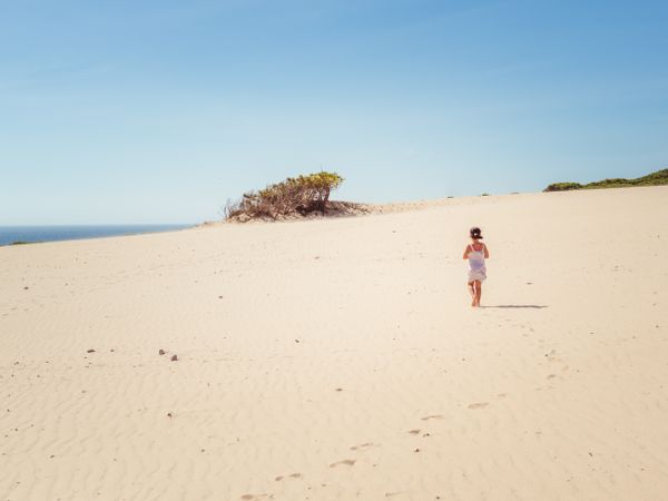 Cute little girl walking on sand dune