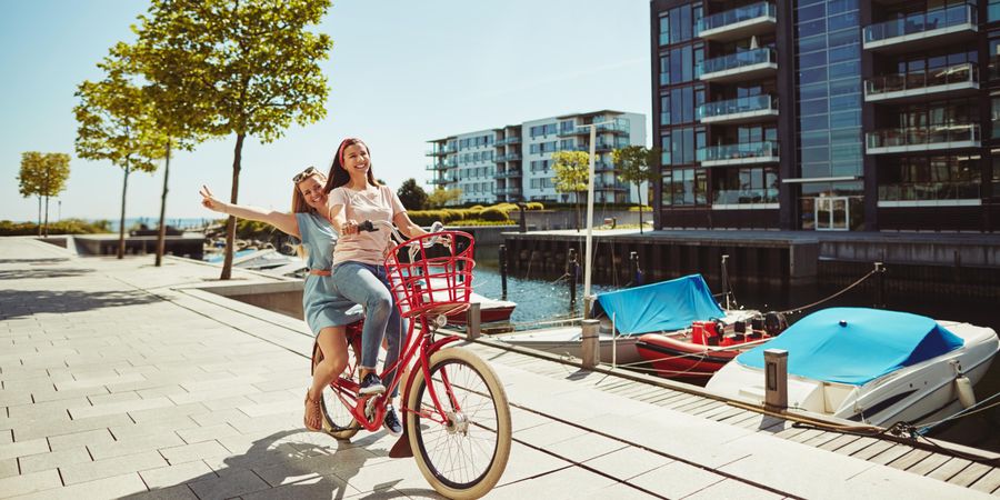 Two close female friends laughing while walking and talking along the waterfront