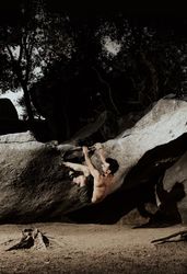 Man practicing rock climbing among large rocks in a forest