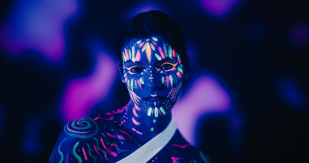 Neon-Painted Body and Face Contrasting Beautifully with Dark Abstract Backdrop