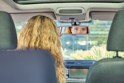 Woman in car looking in rearview mirror