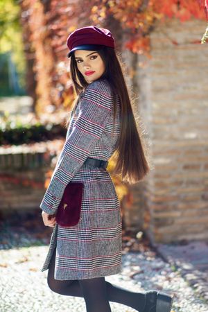 Confident female in warm winter clothes standing outside on sunny day