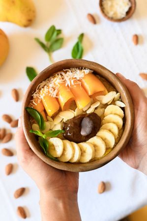 Crop person holding bowl with fruits and nuts