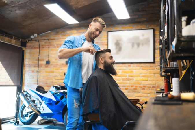 Smiling bearded man receiving a haircut in a salon