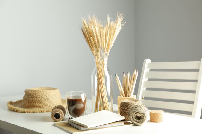 Work table with yarn, notebooks, pencils, dried flowers, with hat and chair