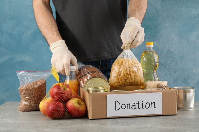 Young man puts groceries in donation box. Volunteer