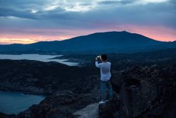 Male with smartphone overlooking the ocean at dusk, landscape