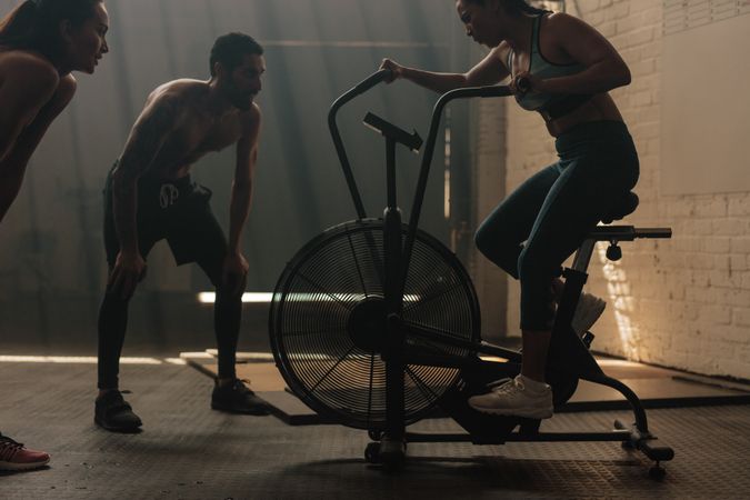 Fitness woman doing spinning at gym with trainers