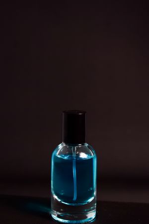Light blue perfume bottle in grey studio with copy space