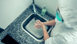 Top view of woman in bacteriological protection suit washing hands