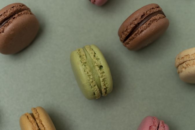 Pastel tasty macaroons over a green background