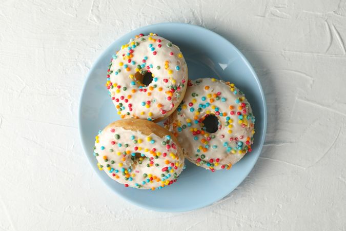 Plate with tasty donuts on plain background