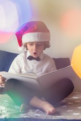 Excited boy in Santa hat reading book