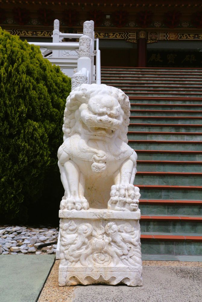 Lion statue guards the steps of a traditional temple in serene surroundings