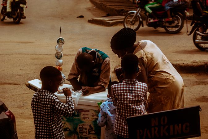 Family of four standing at a small table outdoor in the street of Lagos