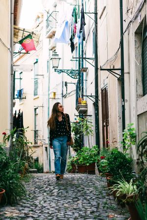 Young casual brunette walking on cobblestone street of old city