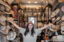 A young Hispanic woman is having fun in a traditional hat shop