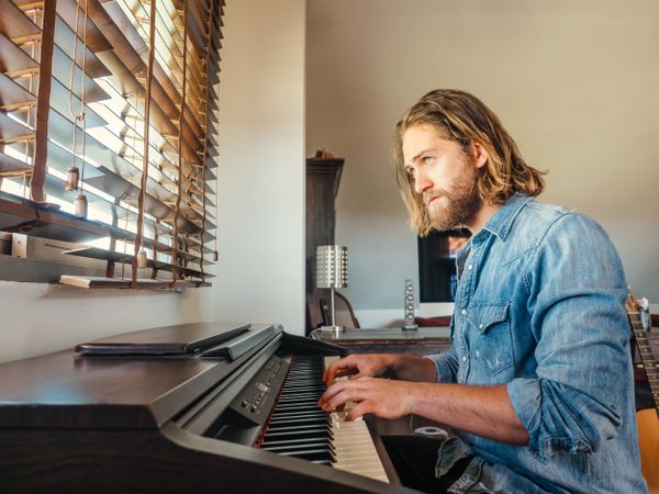 Thoughtful male playing synthesizer at home