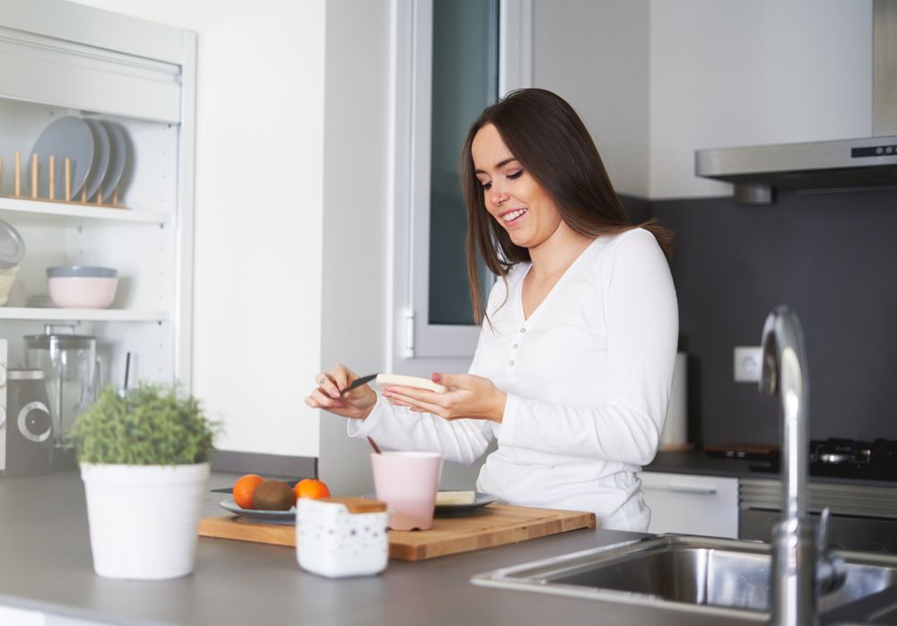 Smiling woman making sandwiches in kitchen