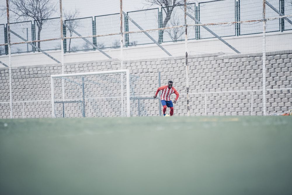 Black soccer player with red equipment playing soccer.
