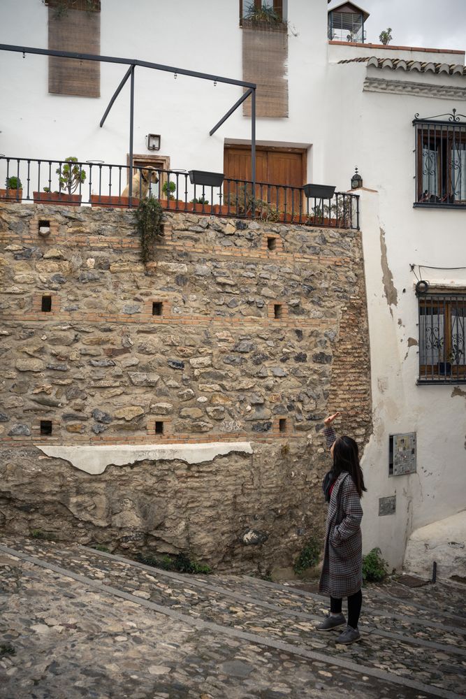 Asian female on aged cobblestone steps in city alley