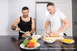 Male couple preparing vegetables and cutting bread for lunch 4AQWQ4