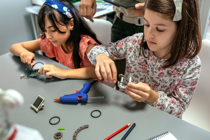 Students assembling machine pieces with teacher helping their in a robotics class.