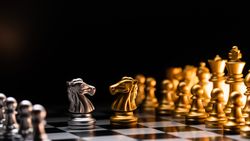 Duel of knights. Silver against gold on chessboard.