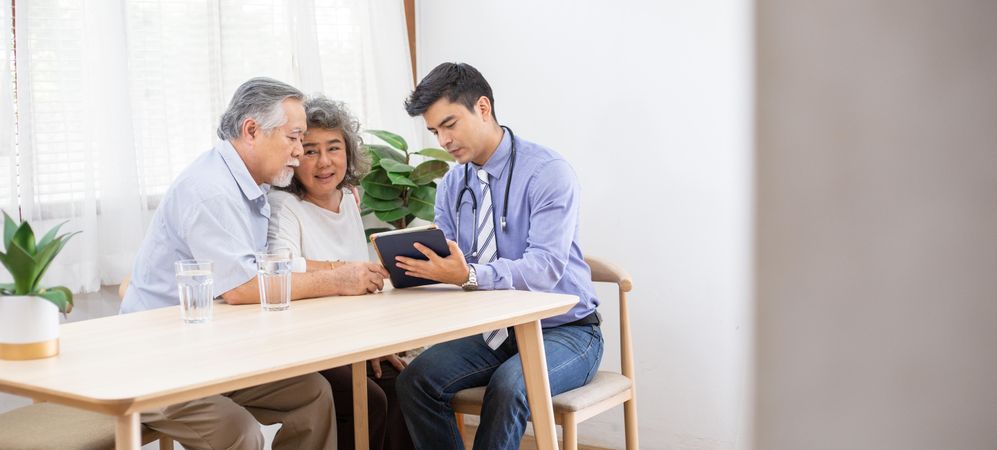 Doctor using digital tablet discussing test result and diagnosis to Asian patients