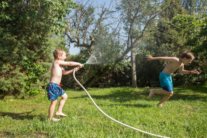 Little kids in swimwear having fun with splashing water