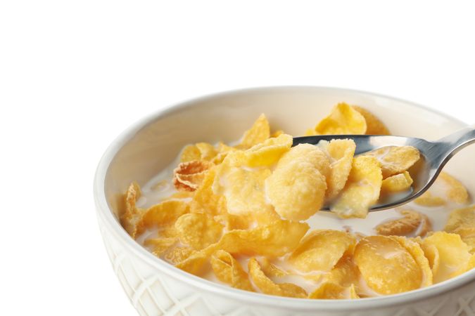Spoon and bowl of muesli with milk isolated on plain background