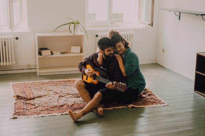 Cheerful couple playing guitar at home