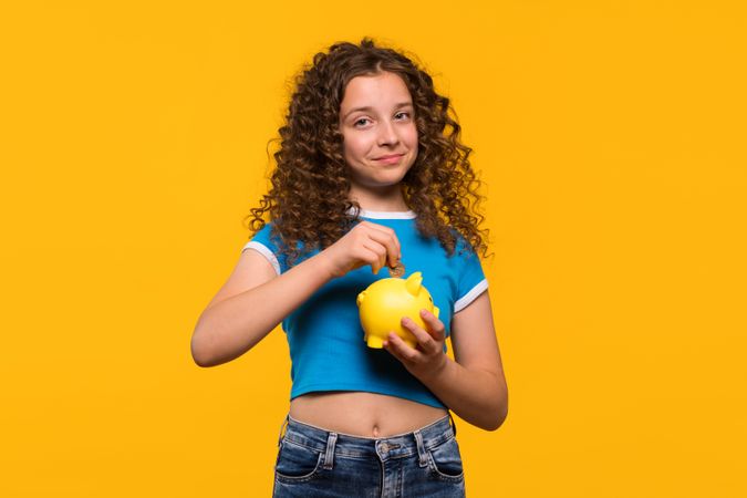 Girl putting a coin into a piggy bank